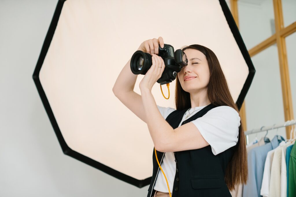Female Photographer Smiling While Working in a Studio with Professional Lighting Equipment Symbolizing the Benefits of Joining a Photography Mastermind