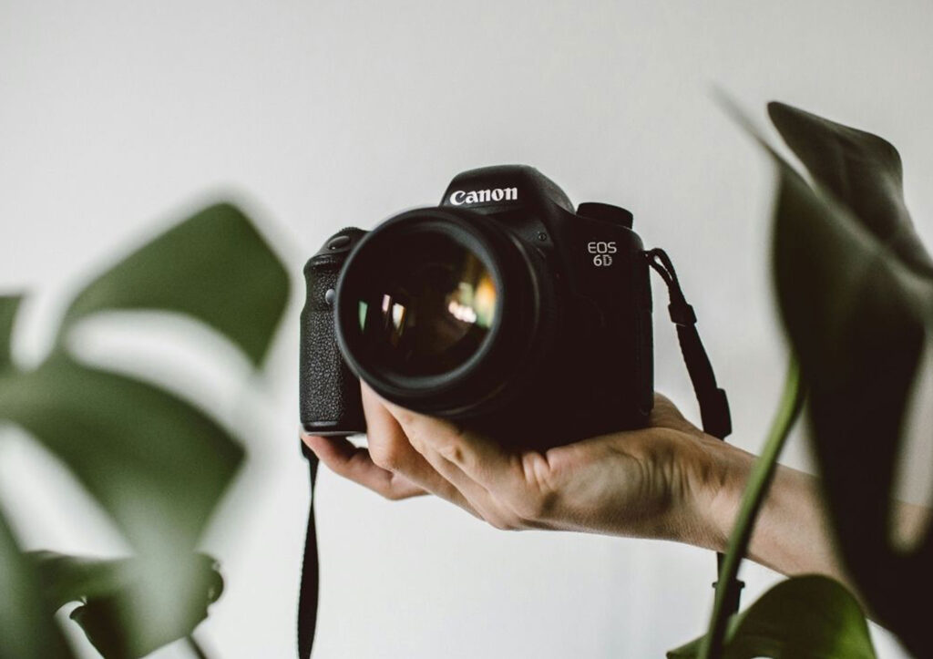 Hand Holding a Canon Eos d Camera with Greenery in the Background Symbolizing How the Best Seo Keywords for Photographers Can Help Capture More Visibility Online