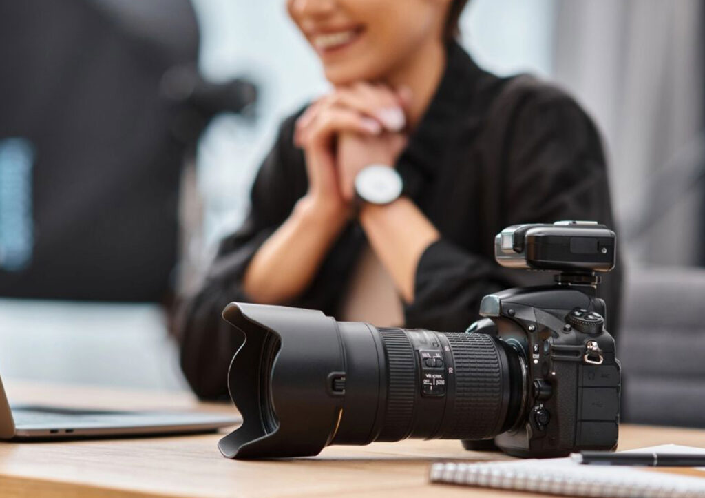 Close up of a Professional Dslr Camera on a Desk with a Smiling Photographer in the Background Symbolizing the Impact of Using the Best Seo Keywords for Photographers to Grow Online Visibility