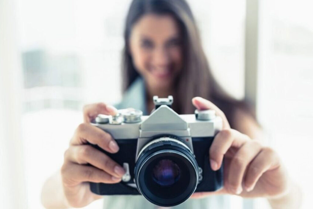 Smiling Woman Holding a Camera Symbolizing Creativity and Connection on a Professional Photographer Homepage
