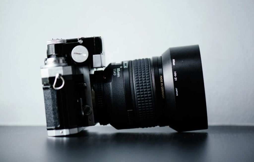 Close-up of a professional camera on a table, representing tools needed to advertise your photography business successfully.
