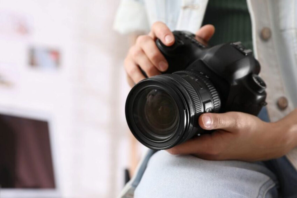 Close-up of a photographer holding a professional DSLR camera, illustrating the role of visuals in Social Media for Photographers.