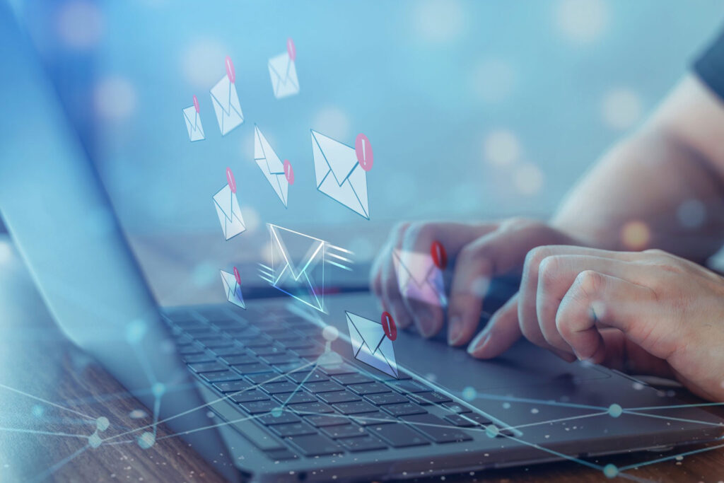 Hands typing on a laptop with floating email icons, illustrating how to be successful with email marketing for photographers.