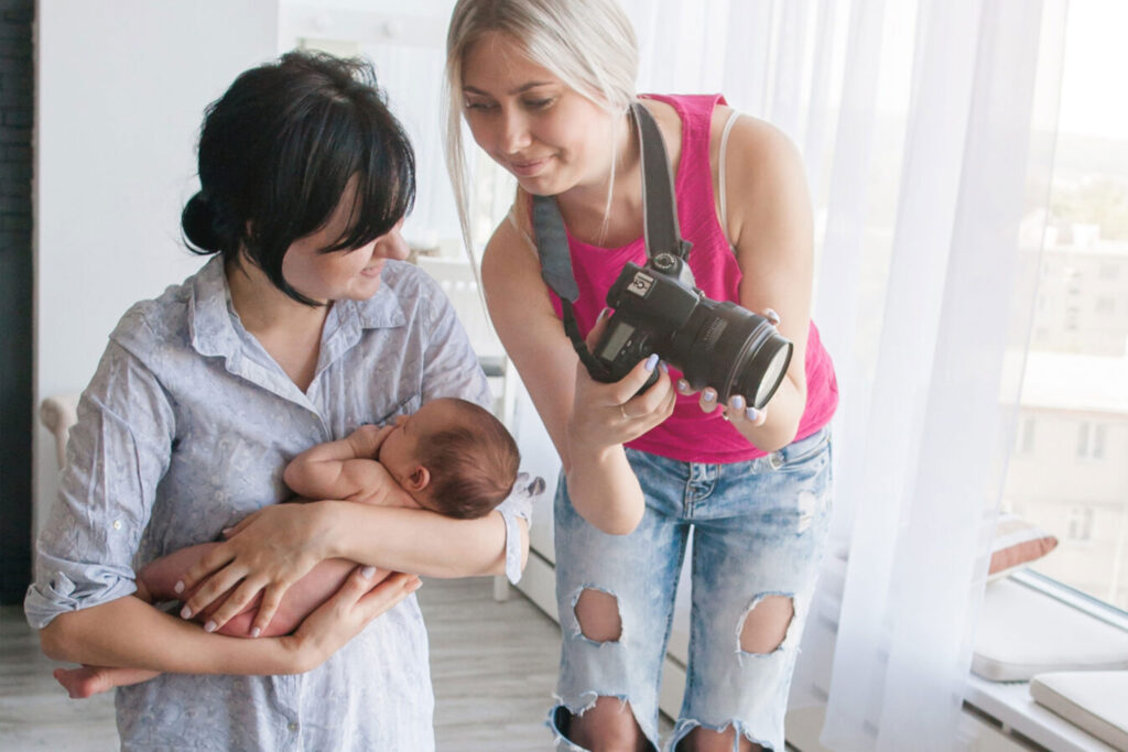 Photographer showing a mother images of her newborn baby, symbolizing SEO for newborn photographers to build trust and attract families.