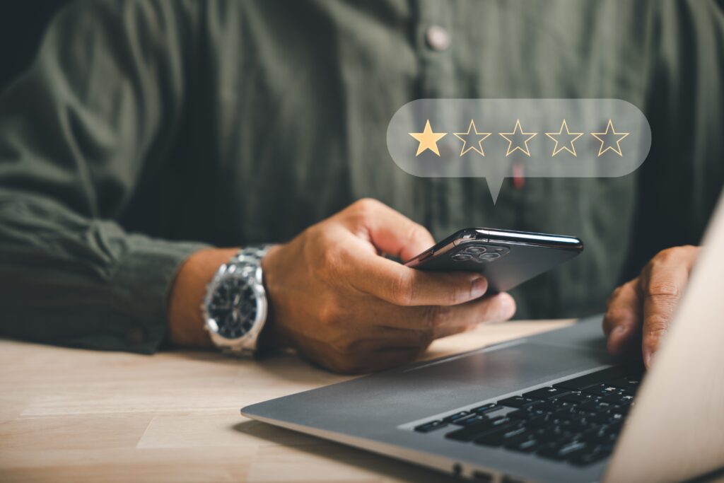 A person using a smartphone and laptop with a five-star rating notification, highlighting proper PR and marketing for photographers matters.