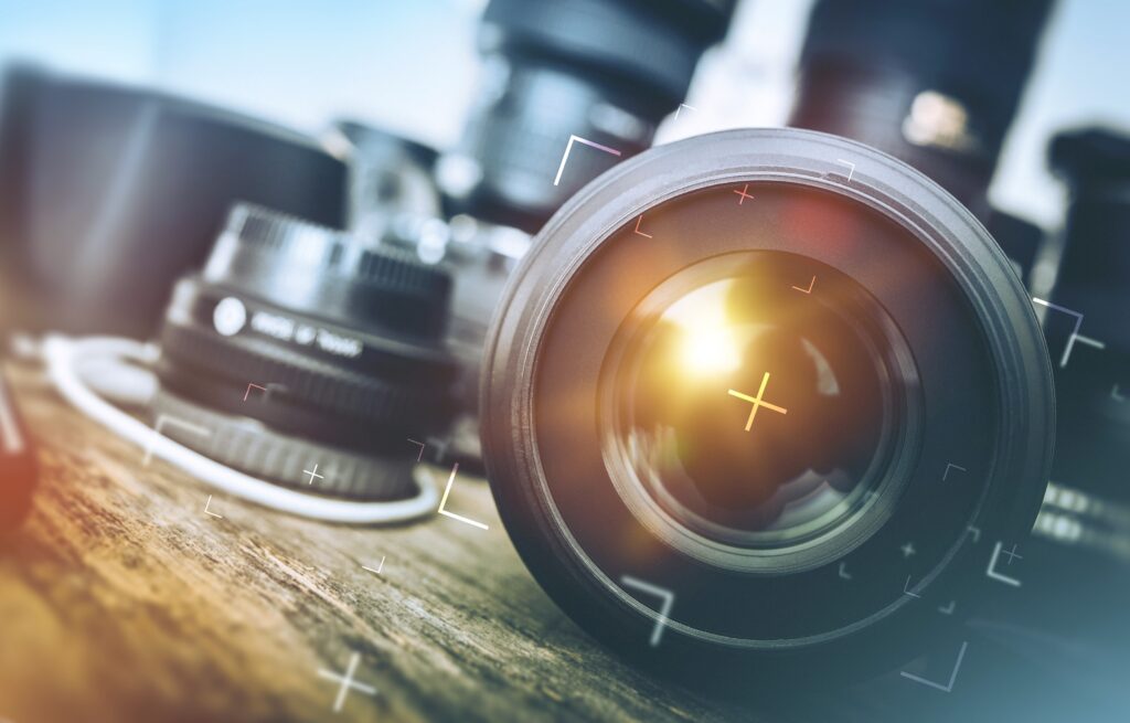 A close-up of camera lenses on a wooden surface with a focus target, representing a professional SEO company for photographers.