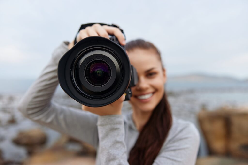 Smiling Photographer Holding a Camera Up Close to the Lens Outdoors Symbolizing Creativity and Content Creation on Instagram for Photographers