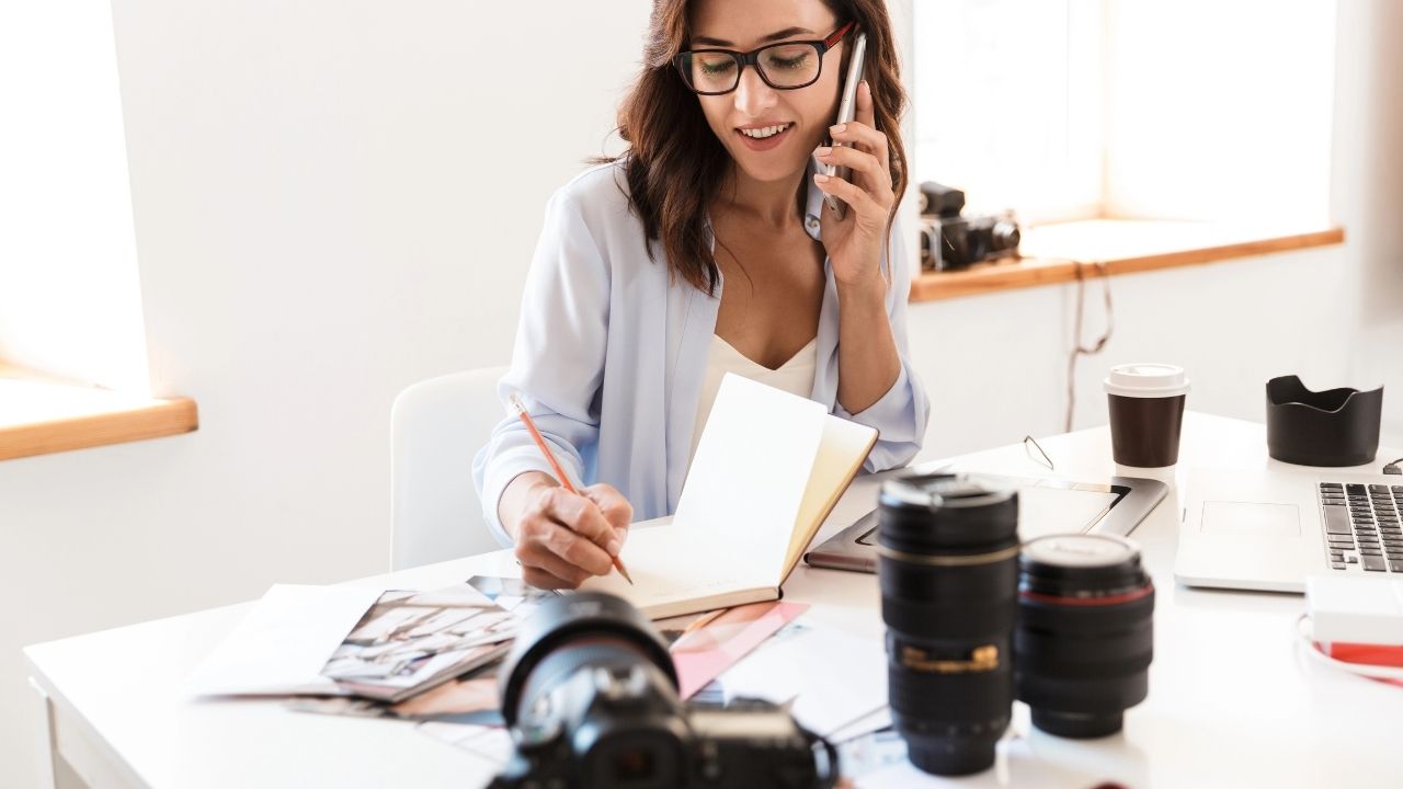 Female photographer working at her desk with camera gear and laptop, symbolizing the role of Google Ads for photographers in building consistent high-value bookings.