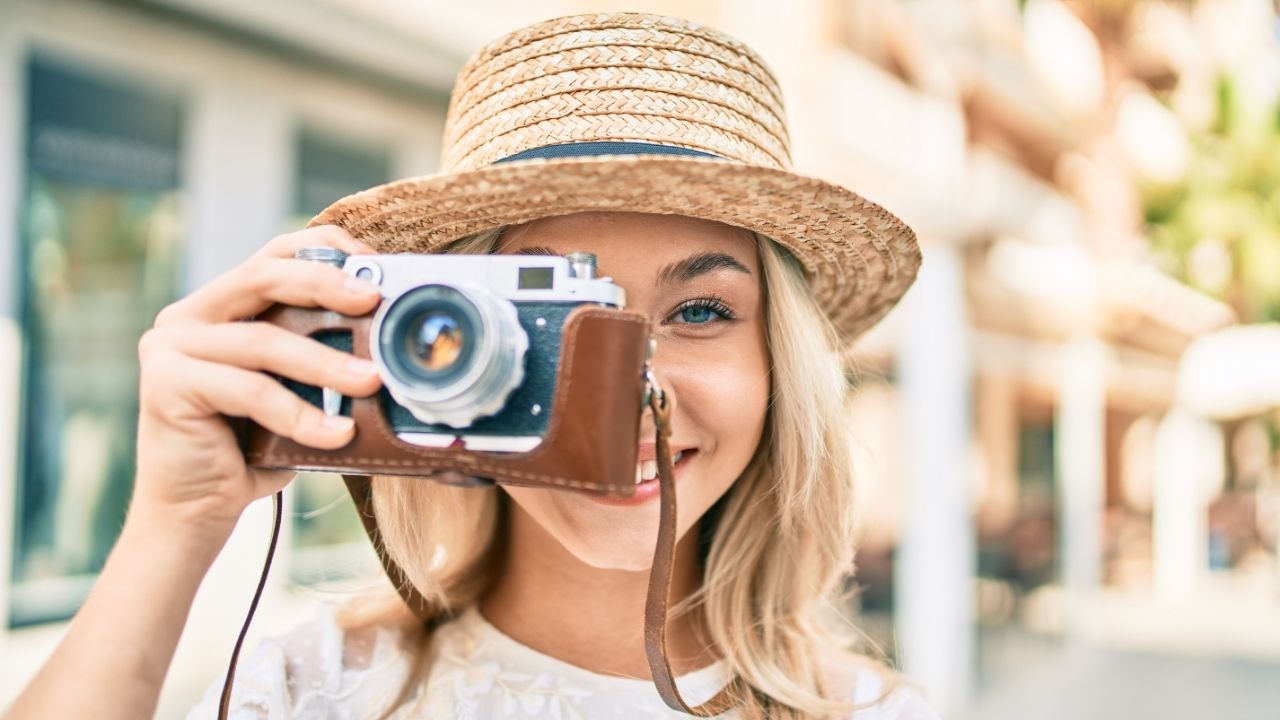 Smiling woman with a vintage camera outdoors, representing effective use of hashtags for Instagram photographers to grow visibility and bookings.
