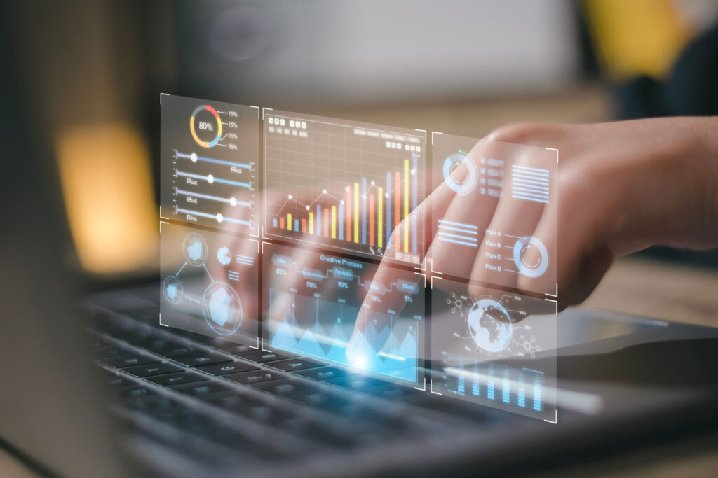 Hands typing on a laptop with digital graphs and charts, representing analytics and strategies for how to get commercial photography clients.