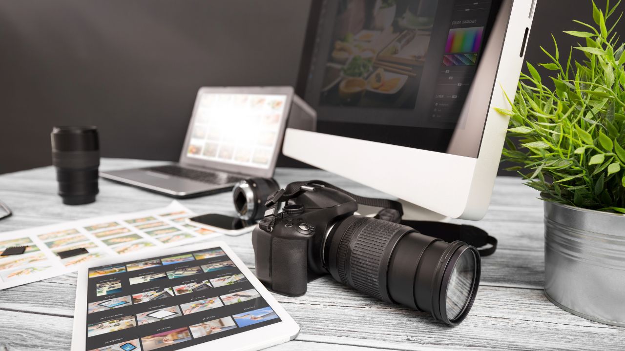 Professional camera, laptop, and tablet displaying edited images on a desk, representing photography advertising examples.