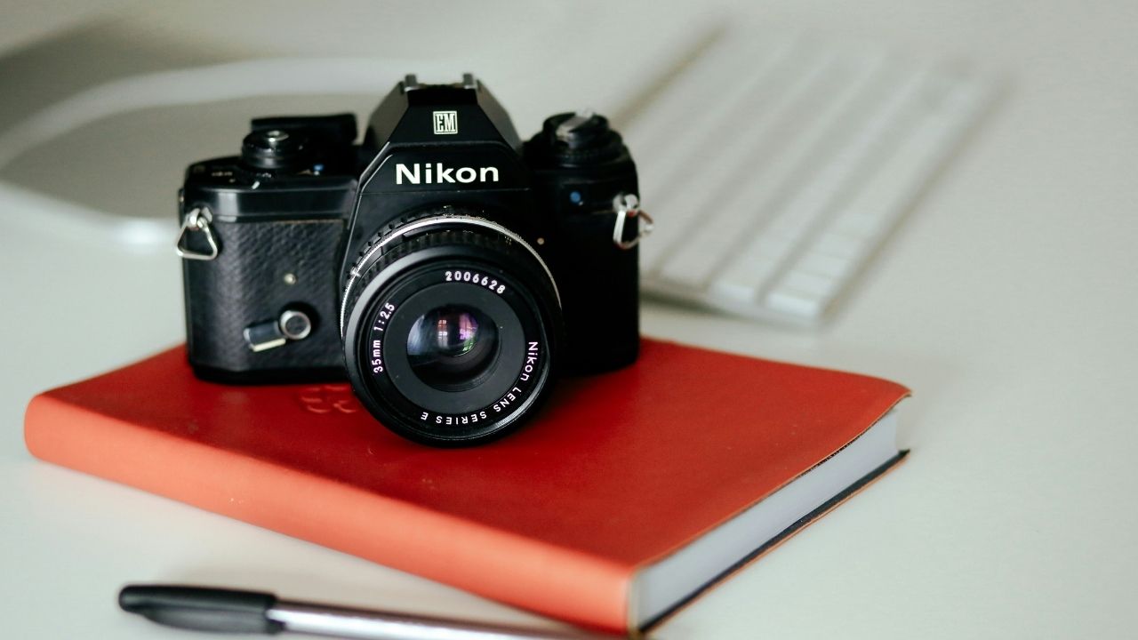 Vintage Nikon film camera on a red notebook, symbolizing strategy and planning in photography business coaching.