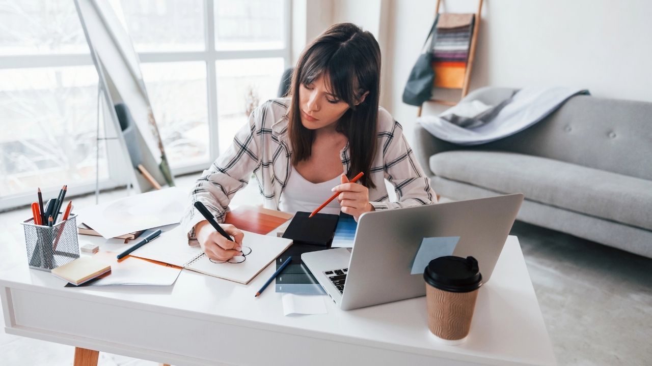 Photographer working at a desk with laptop and notebook, planning social media strategy, illustrating practical social media for photographers tips.