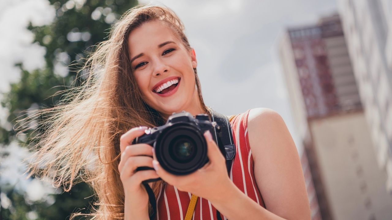 Smiling photographer holding a camera outdoors, symbolizing the community and growth benefits of a photography mastermind.
