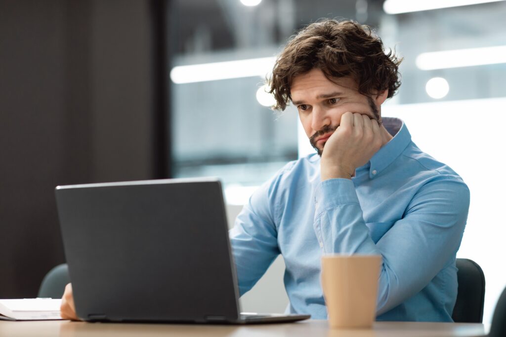 Frustrated photographer looking at a laptop, questioning is SEO still worth it for photographers in today’s digital marketing landscape.