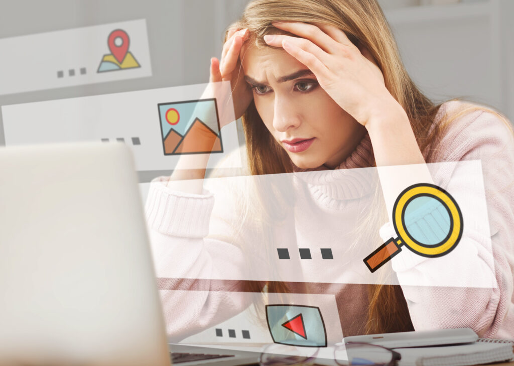 A frustrated photographer working on a laptop with scattered notes, illustrating the challenges of DIY SEO for photographers.