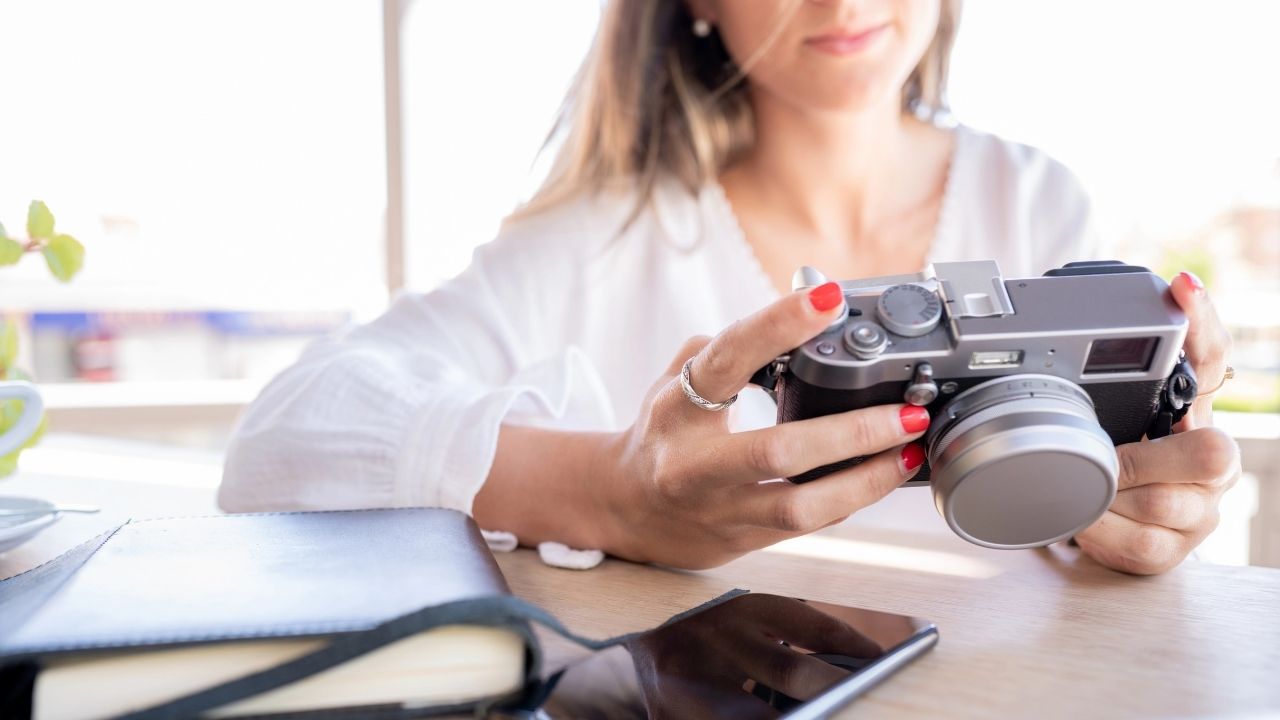 Close-up of a photographer holding a camera at a desk, representing why every photographer needs a mentor to grow skills and confidence in their career.