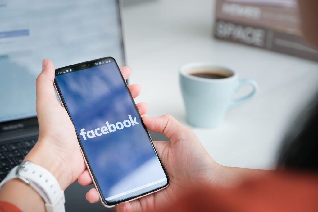 Person Holding a Smartphone with the Facebook App Open Symbolizing the Role of Social Media for Photographers in Marketing and Client Growth