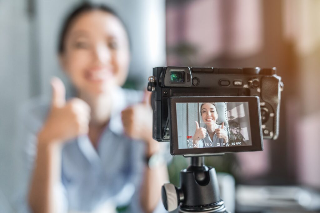 Woman recording a video giving thumbs up on camera, symbolizing Content Marketing for Photographers.