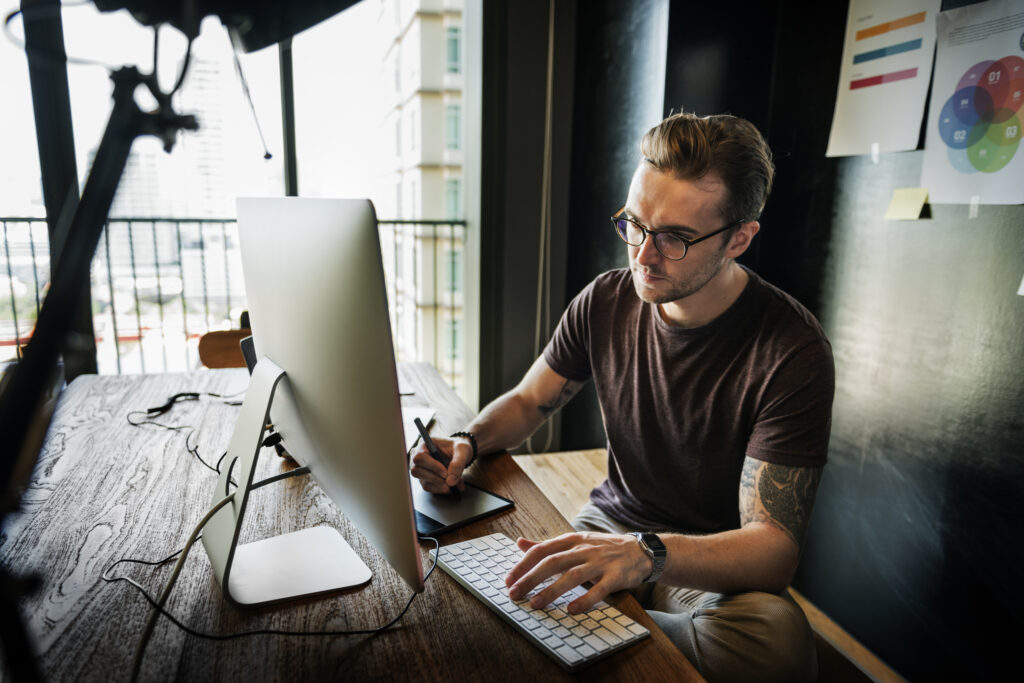 Photographer at desk editing images on a computer with camera gear nearby, reflecting on is a Google Business Profile still worth it for photographers.
