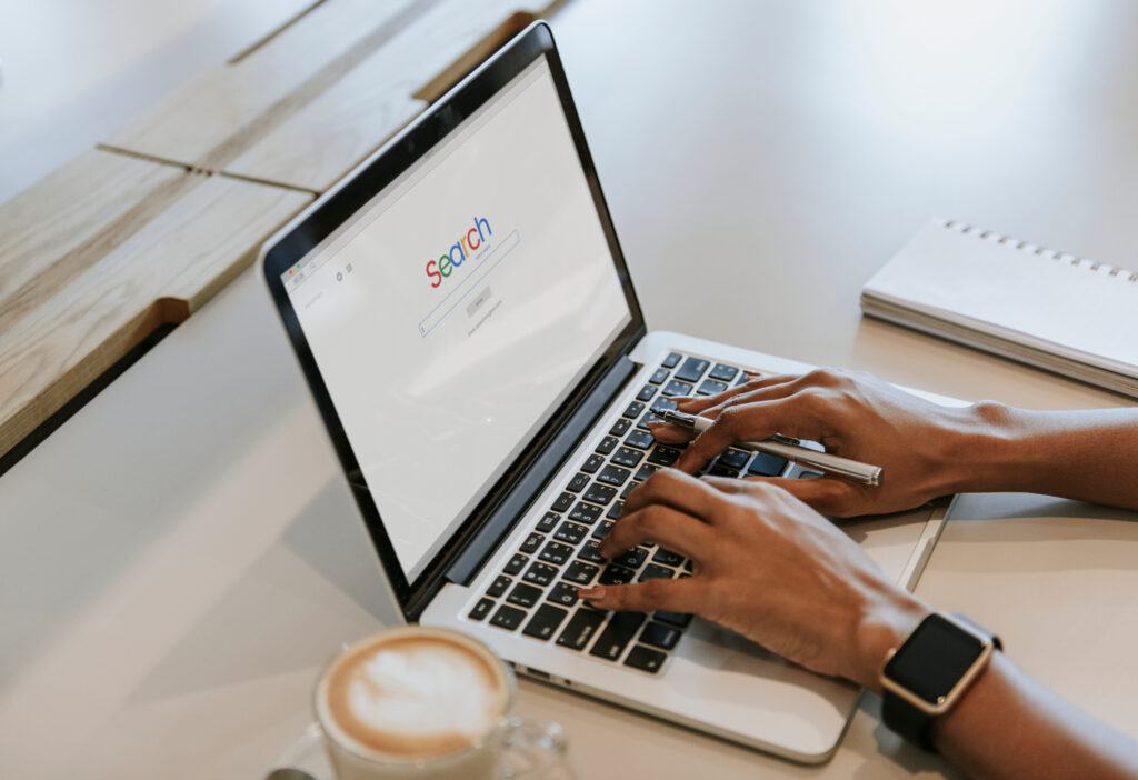 Person typing on a laptop with a search engine on the screen, symbolizing SEO for engagement photographers looking to book more couples.