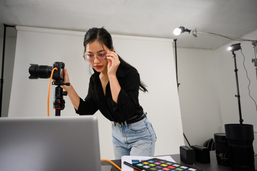 Photographer Adjusting Camera in a Studio While Reviewing Work on a Laptop Representing Gallery Pages That Sell and Convert Visitors into Paying Clients