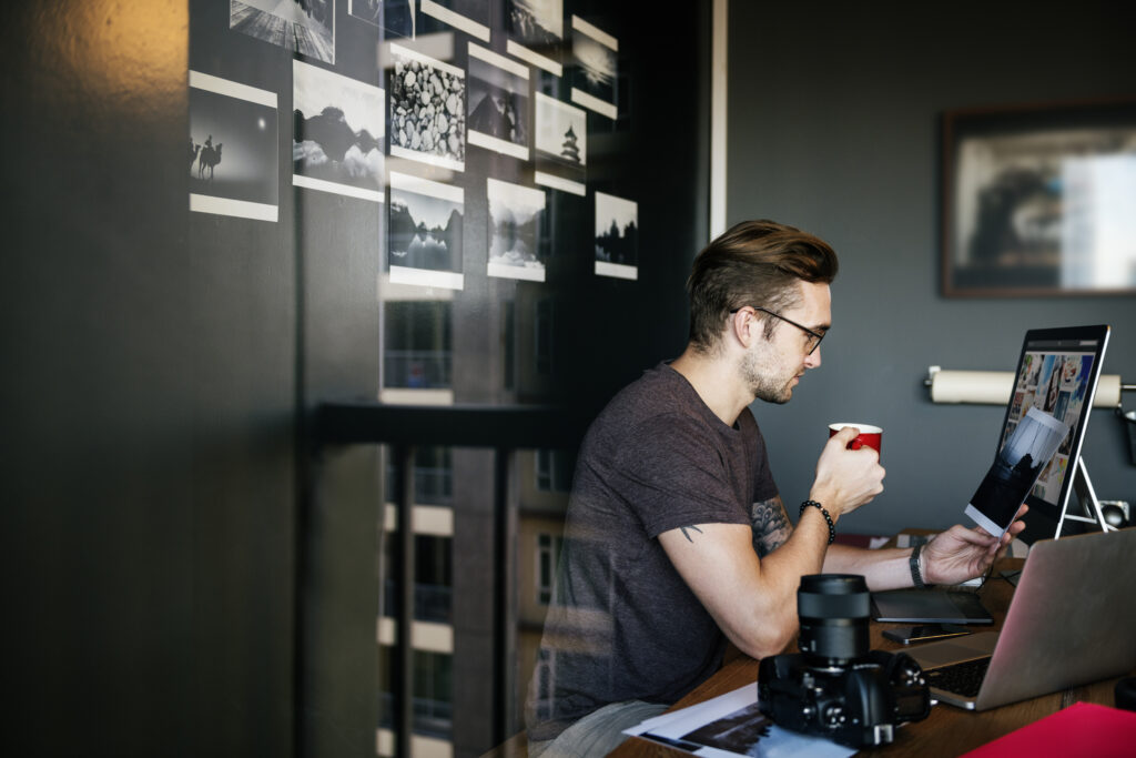 Photographer working at a desk with camera equipment and computer, considering is a Google Business Profile still worth it for photographers today.