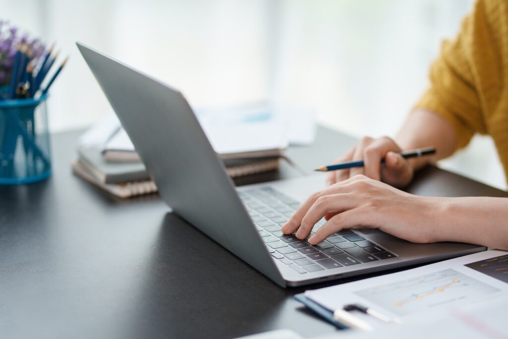 Photographer working on a laptop with charts and notes, representing photography advertising examples for planning campaigns.