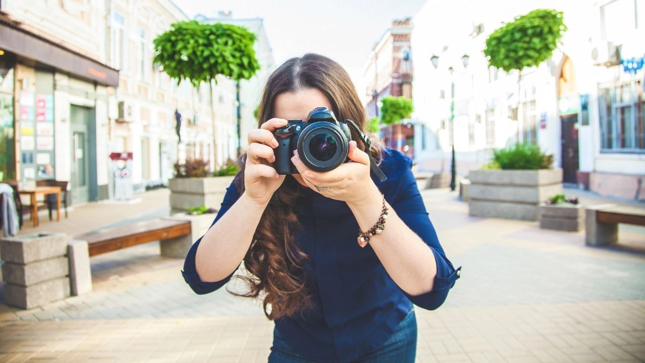 Photographer holding a camera on a city street, representing the balance between visibility and strategy explored in PR vs Paid Ads for Photographers.